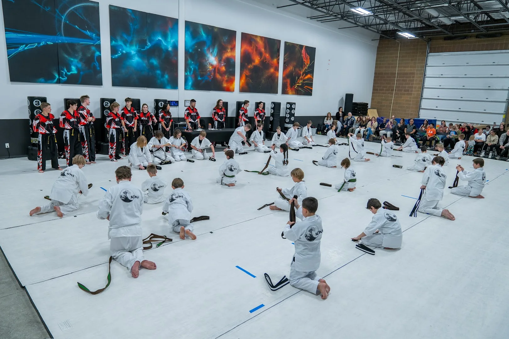 An instructor closely supervising adult karate students on the mat